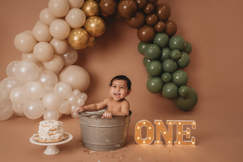 Cake smash milestone session with Atlanta, Georgia cake smash photographer. Milestone photography session with earthy tones, balloon garland and sweet baby boy eating cake for his first birthday.