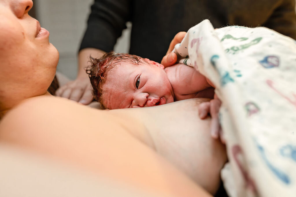 A baby lies on his mother's chest for the first time after being born