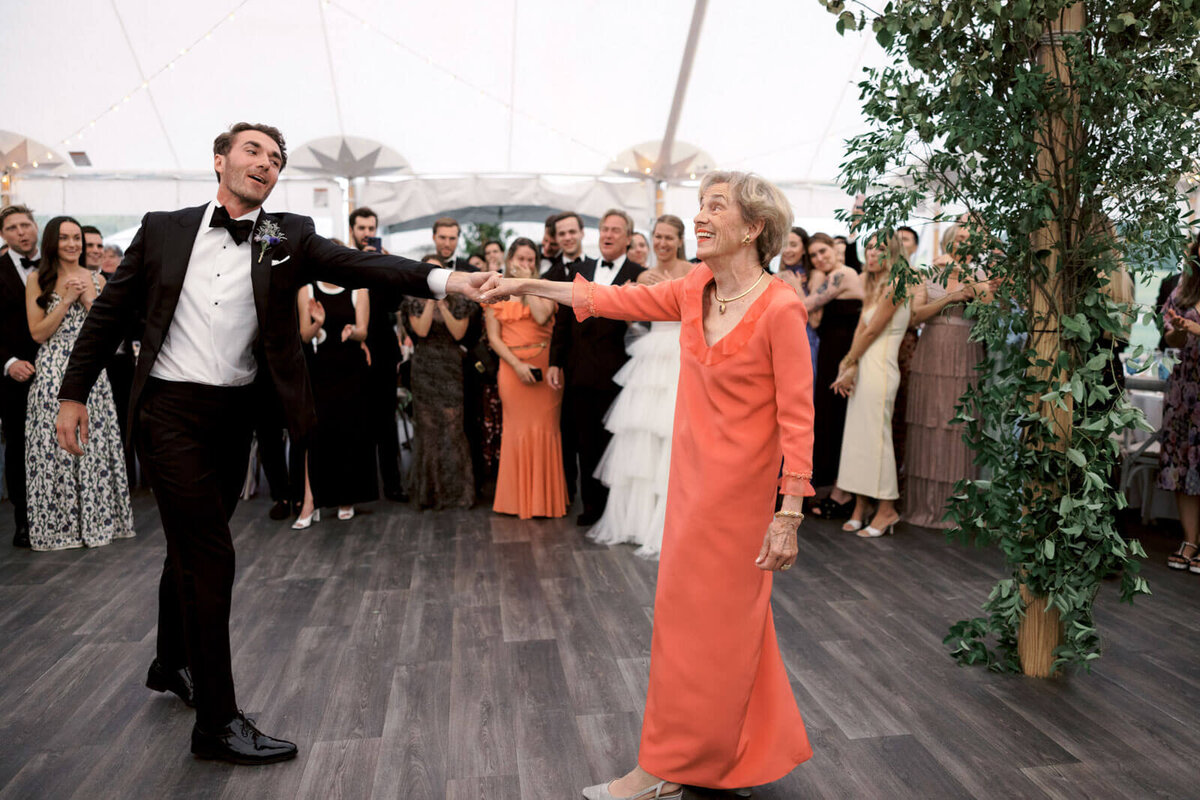The groom is happily dancing with his mother as the guests cheer on at The Ausable Club, NY. Image by Jenny Fu Studio