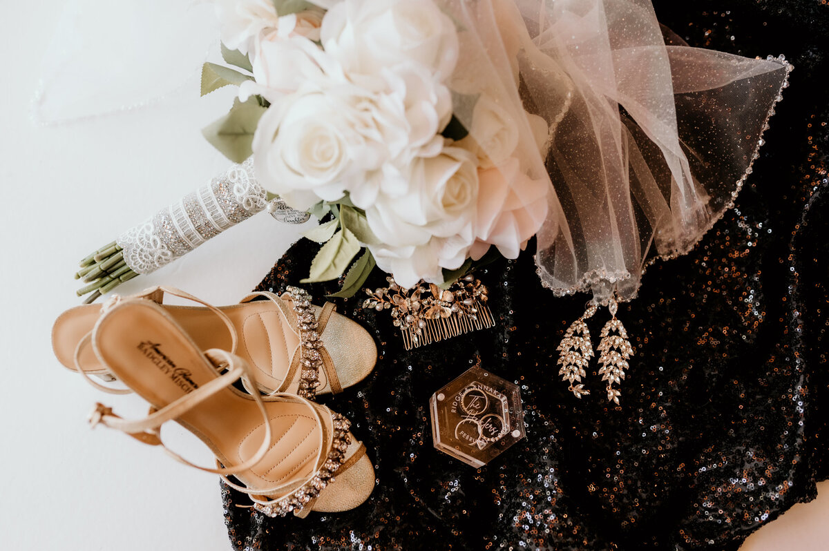bridal bouquet lays next to brides heels and earrings