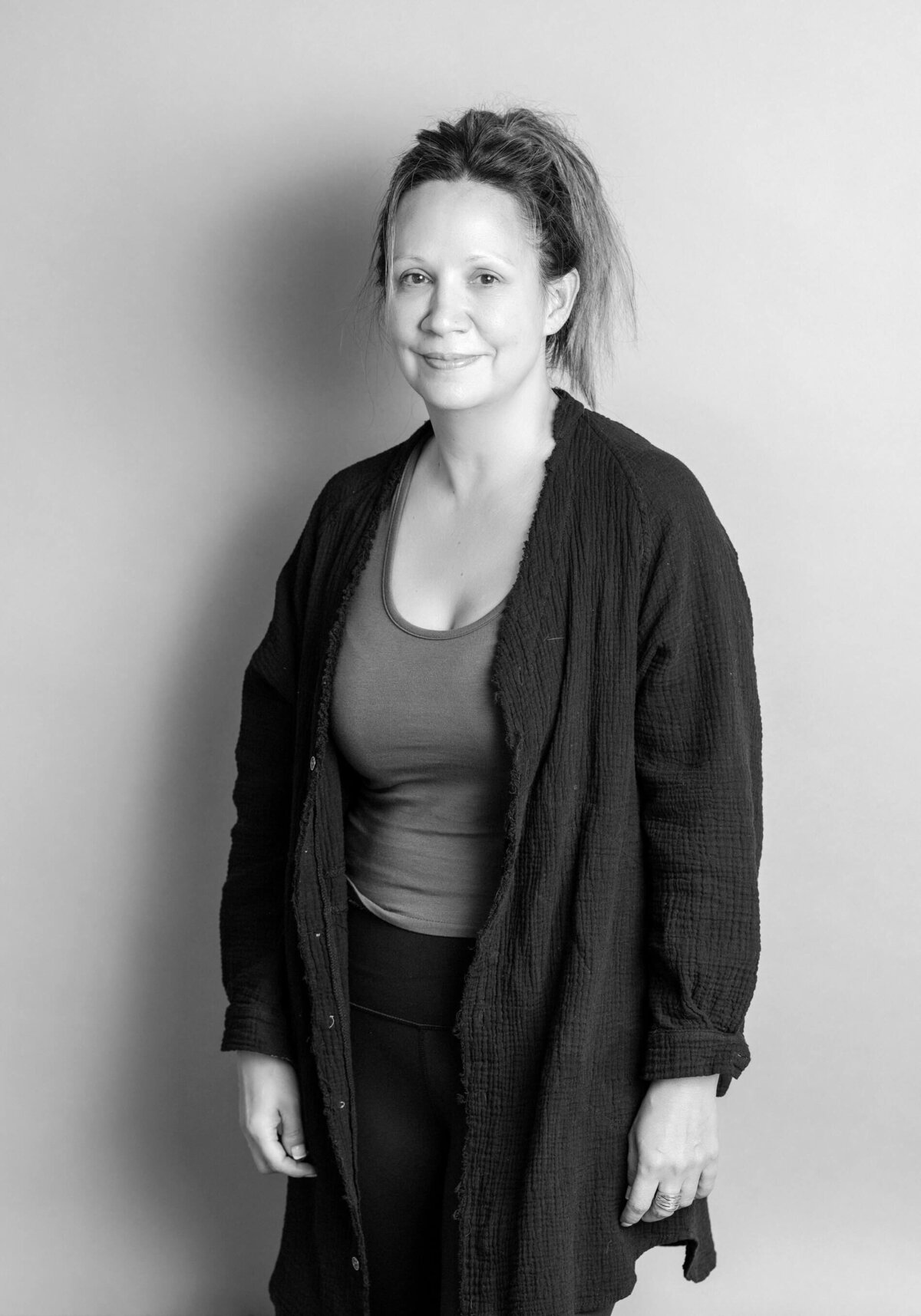 Studio before shot of a woman in a cardigan over a tank top, gazing calmly at the camera.