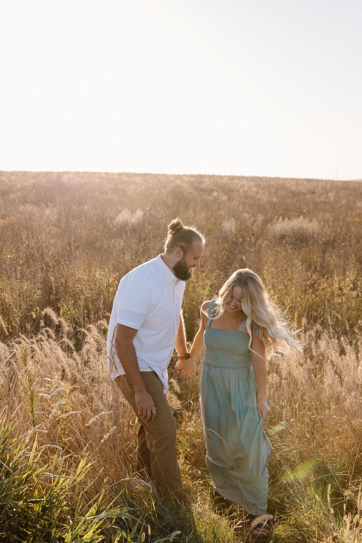 A couple holding hands and walking in a field together