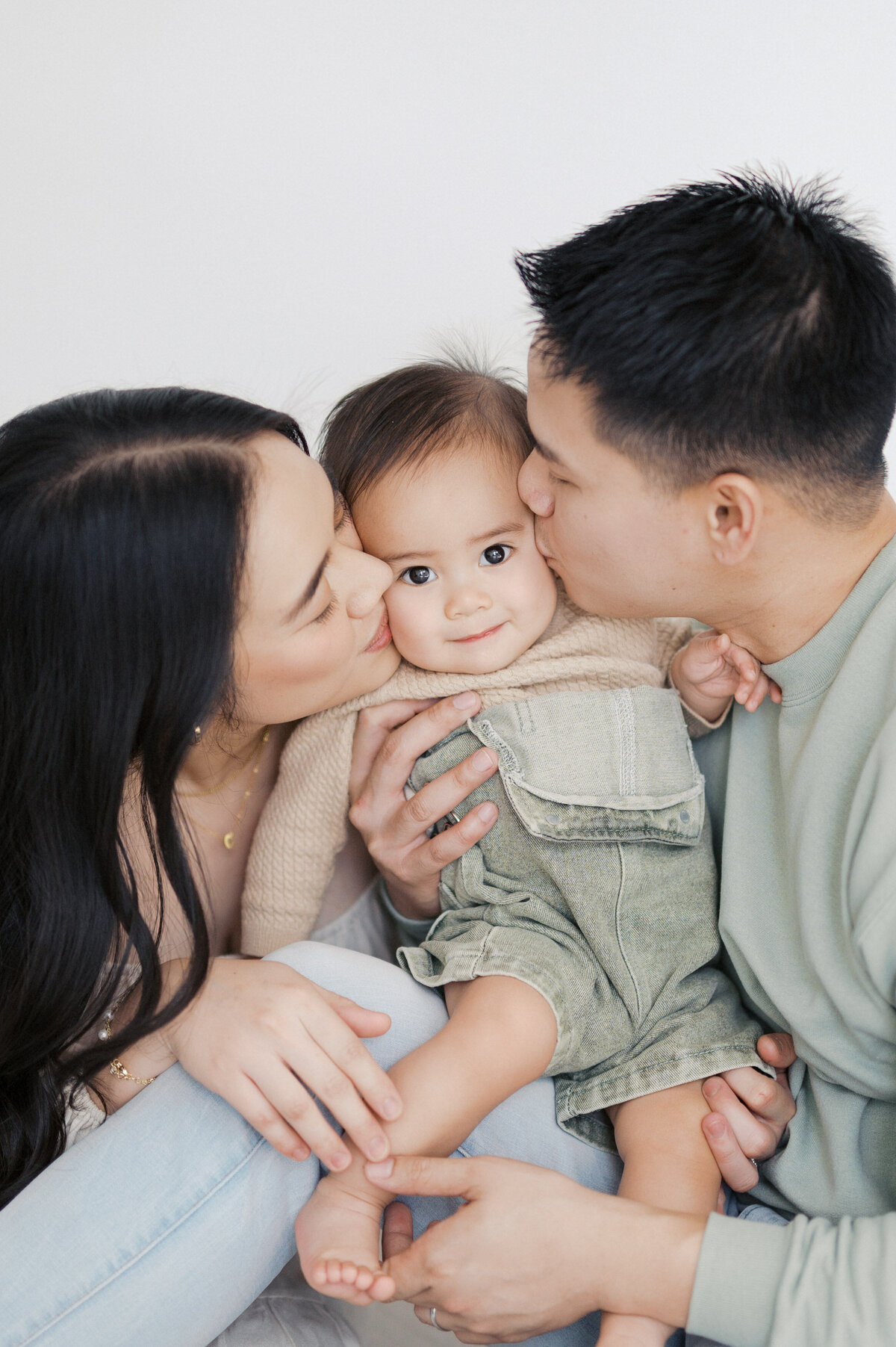 parents kiss cheeks of baby boy during family photography session