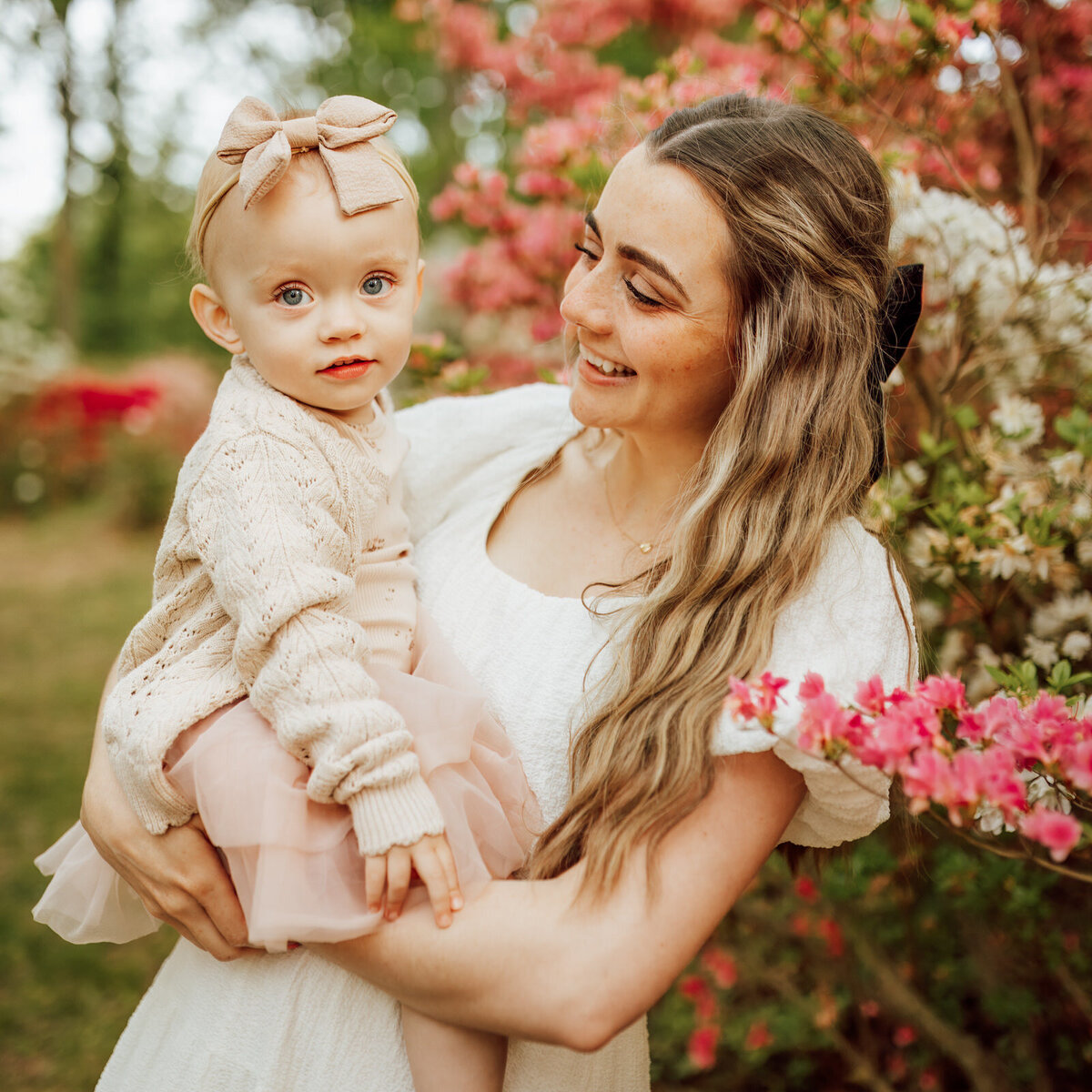 Mother smiling while holding her 18 month old daughter at a photoshoot in an Azalea garden in Maryland
