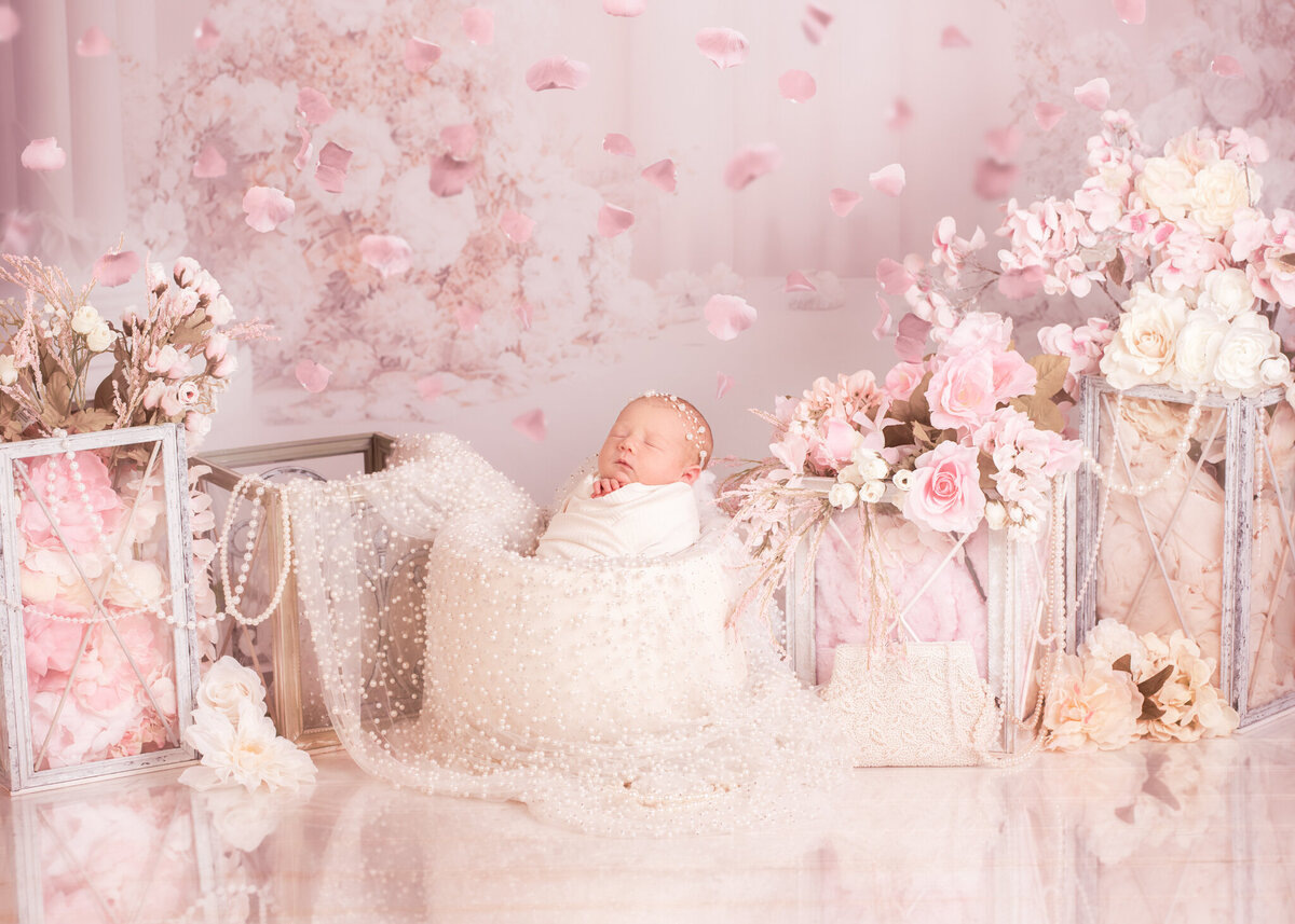 Newborn lying on a soft pink blanket with a dreamy floral backdrop, captured in Overland Park, Kansas. A perfect choice for families seeking sweet and feminine newborn photography