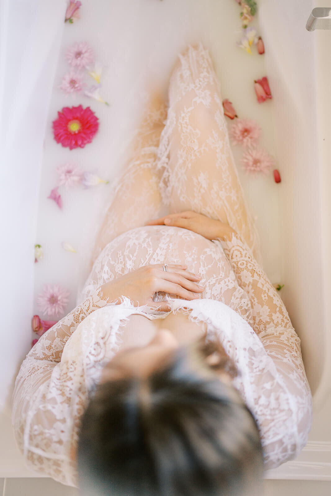 Anticipating joy, an Asian mum in a lace white gown embraces her pregnancy glow at a Gold Coast milk bath maternity photoshoot.