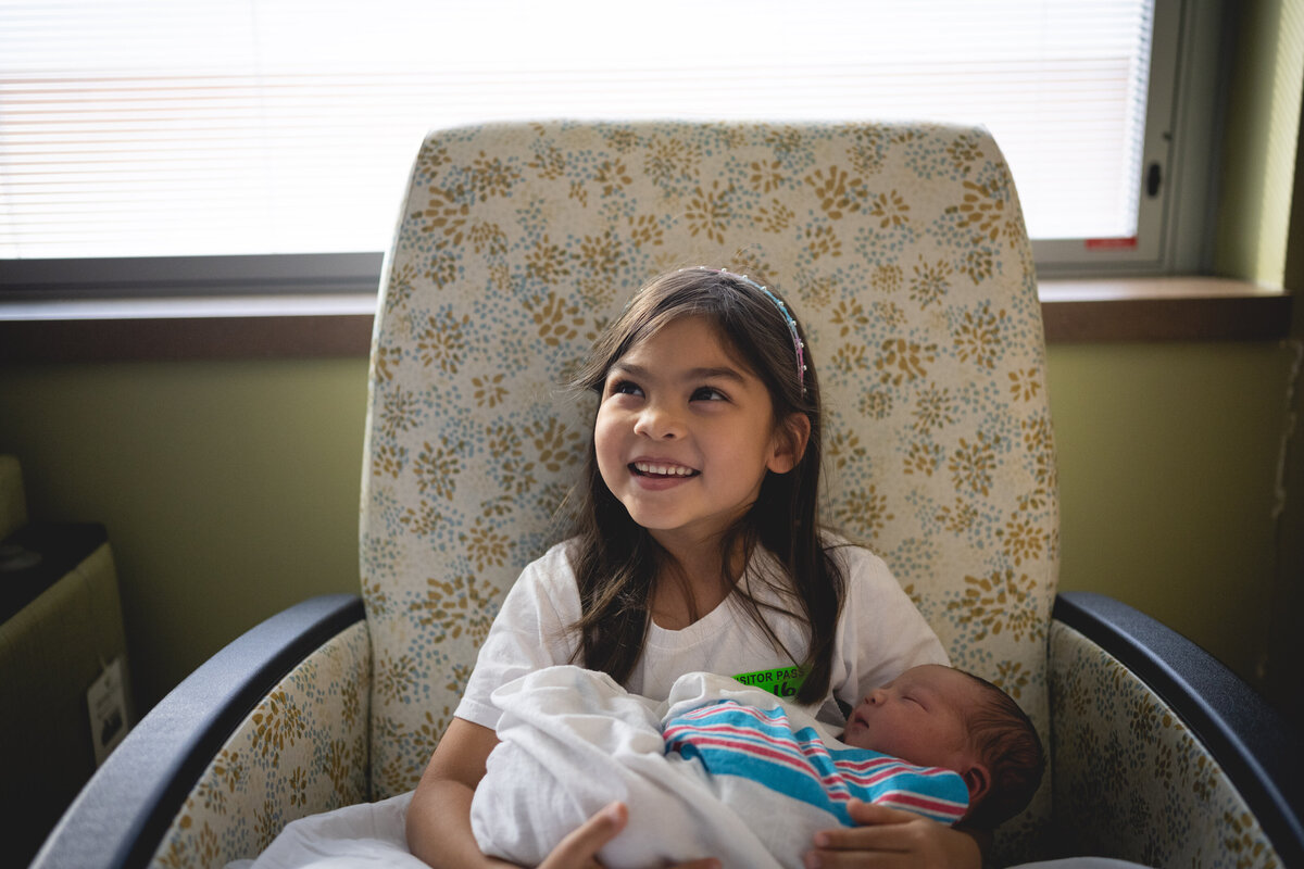Older sister holding newborn baby