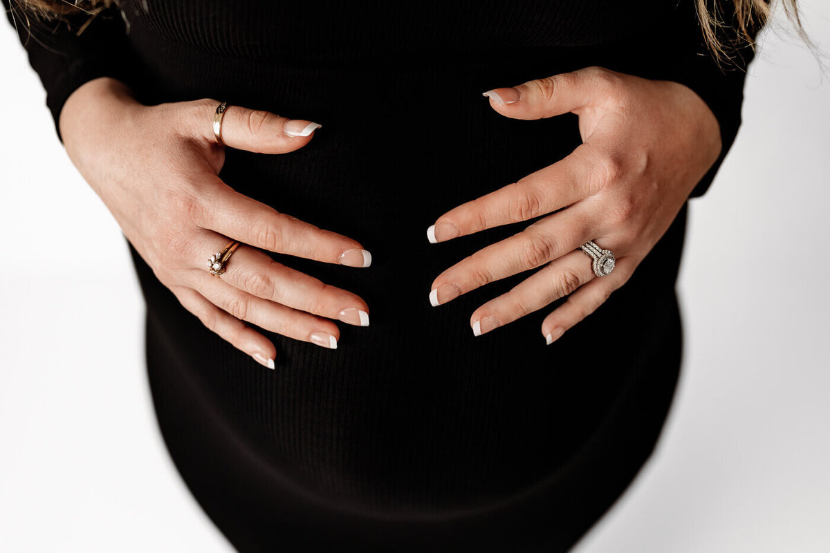 Maternity session in studio mom dressed in black cradling baby bump