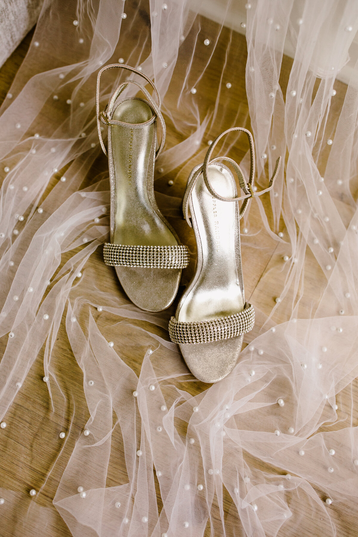 Wedding shoes sitting on veil with pearl details