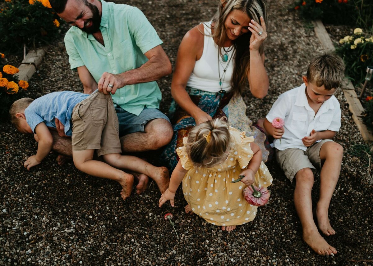 A Pittsburgh family photographer captures a family sitting on the ground in front of a flower garden.