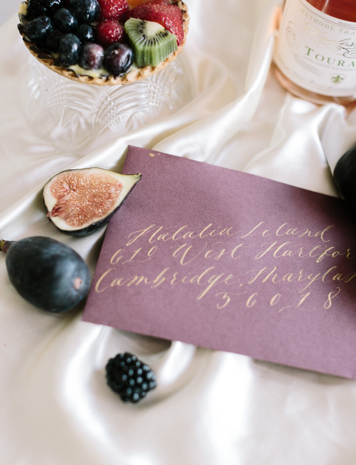 purple envelope with gold ink calligraphy, figs, berries, painterly film brand photography