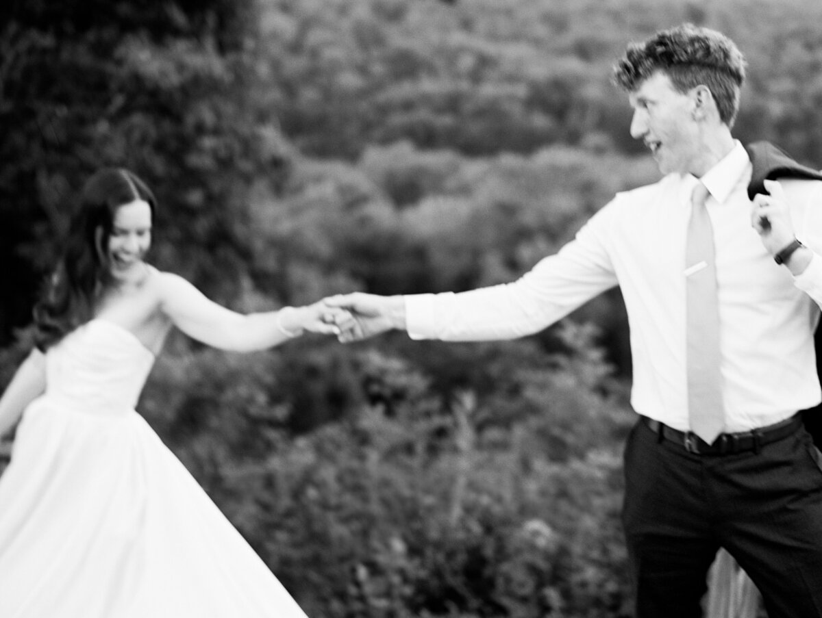 Captured on black and white film, the bride and groom have a dance in the scenic hills of North Carolina, by film photographer My Sun and Stars Co.