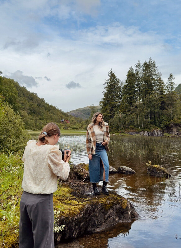 A fashion photographer and model are posing near a lake in Scandinavia