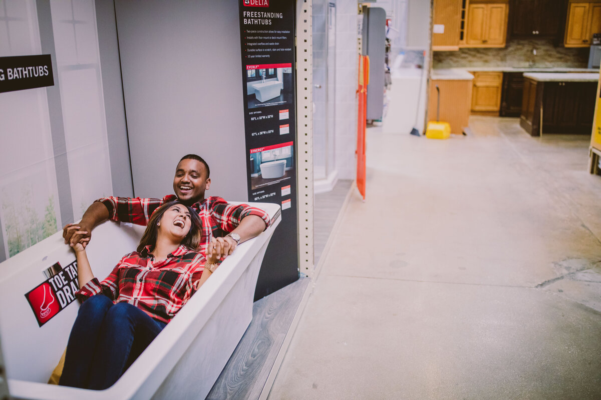 A couple sitting inside a home depot display bathtub during their engagement session