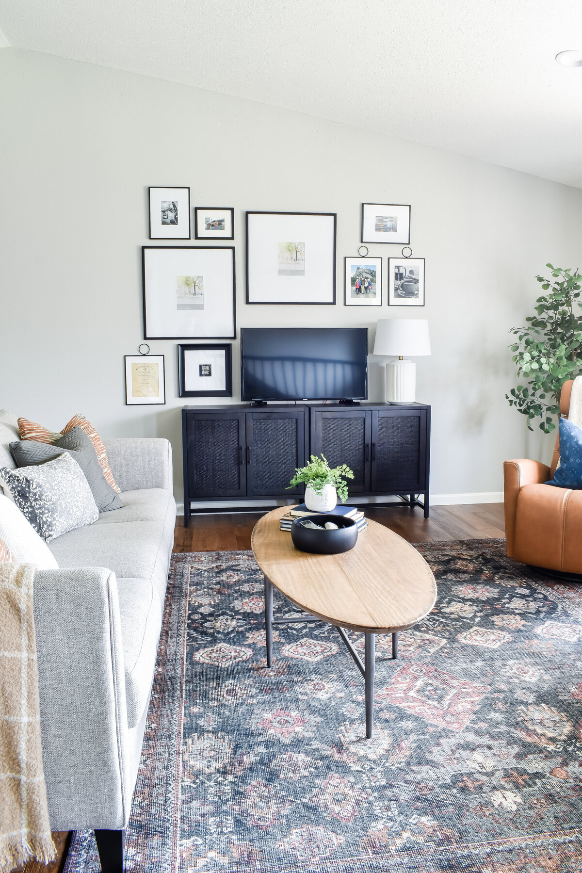 an oval wood coffee table sits in the middle of a living room