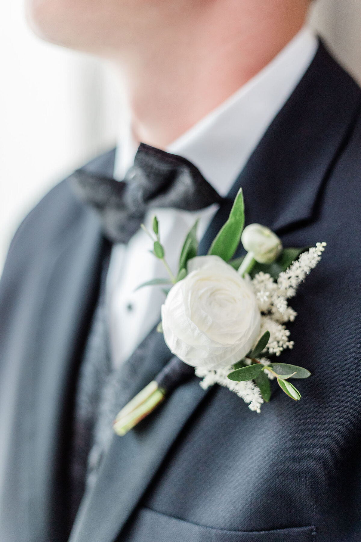 A close of a white boutonniere with black bow tie