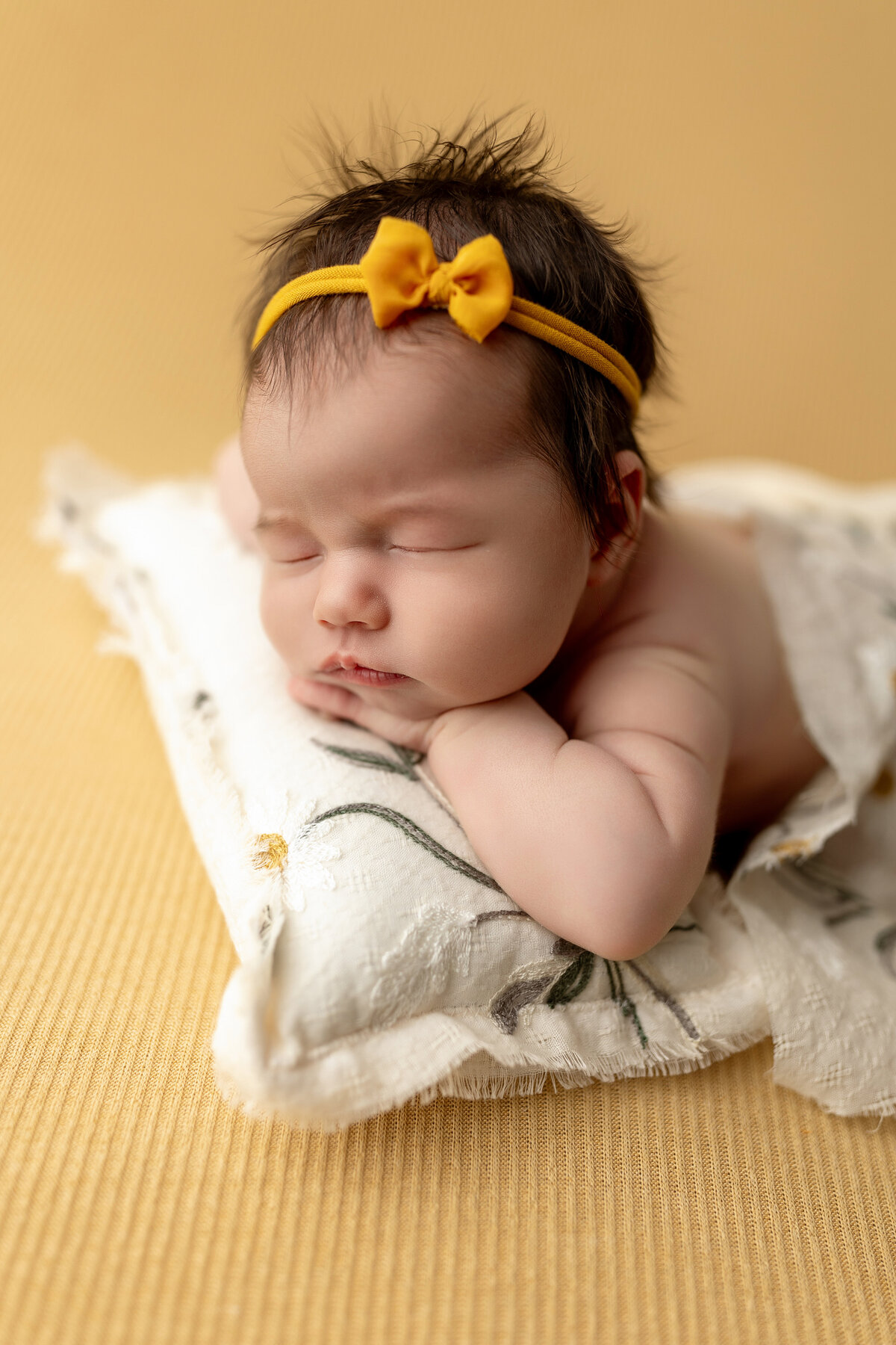 Newborn on yellow backdrop