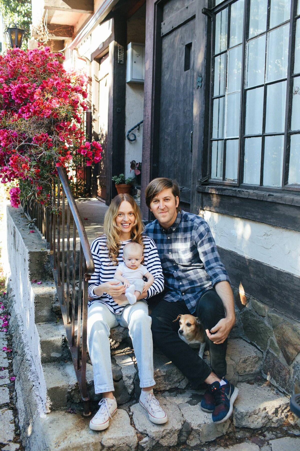 family portrait with baby and dog on a front porch with pink bougainvillea