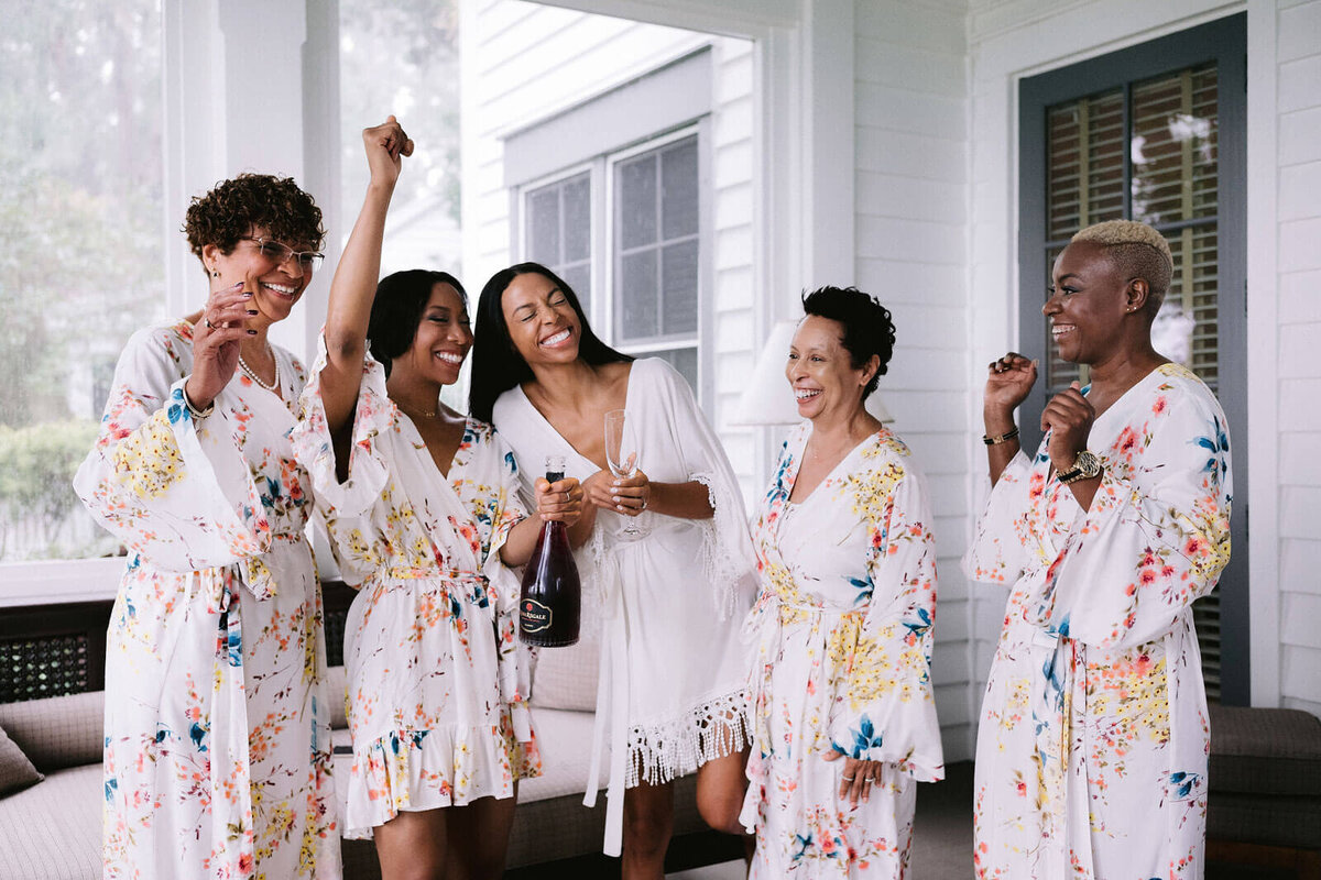 The bride and her bridesmaids in their robes, drinking wine in Montage at Palmetto Bluff. Destination wedding image by Jenny Fu Studio