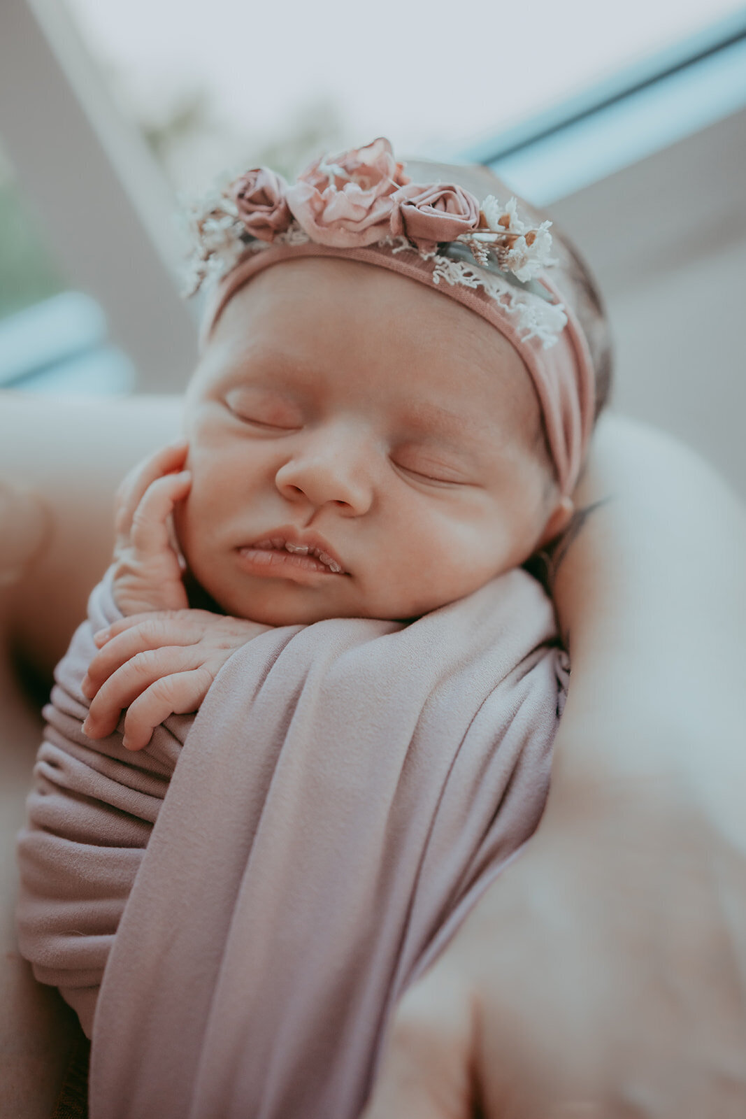 newborn baby girl peacefully sleeps with her hand on her face
