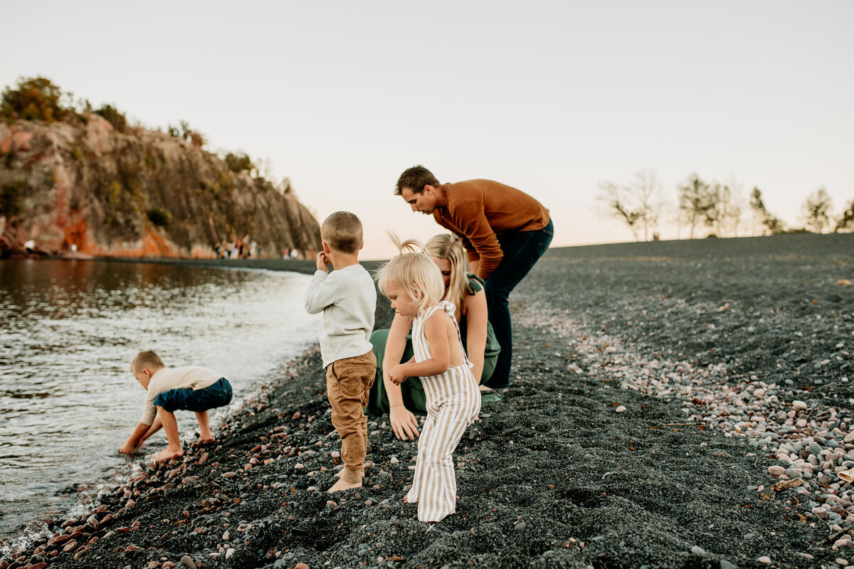 A family of 5 plays along Black Beach in Silver Bay, Minnesota during summer family photos taken by Emmie Verdell Photo.