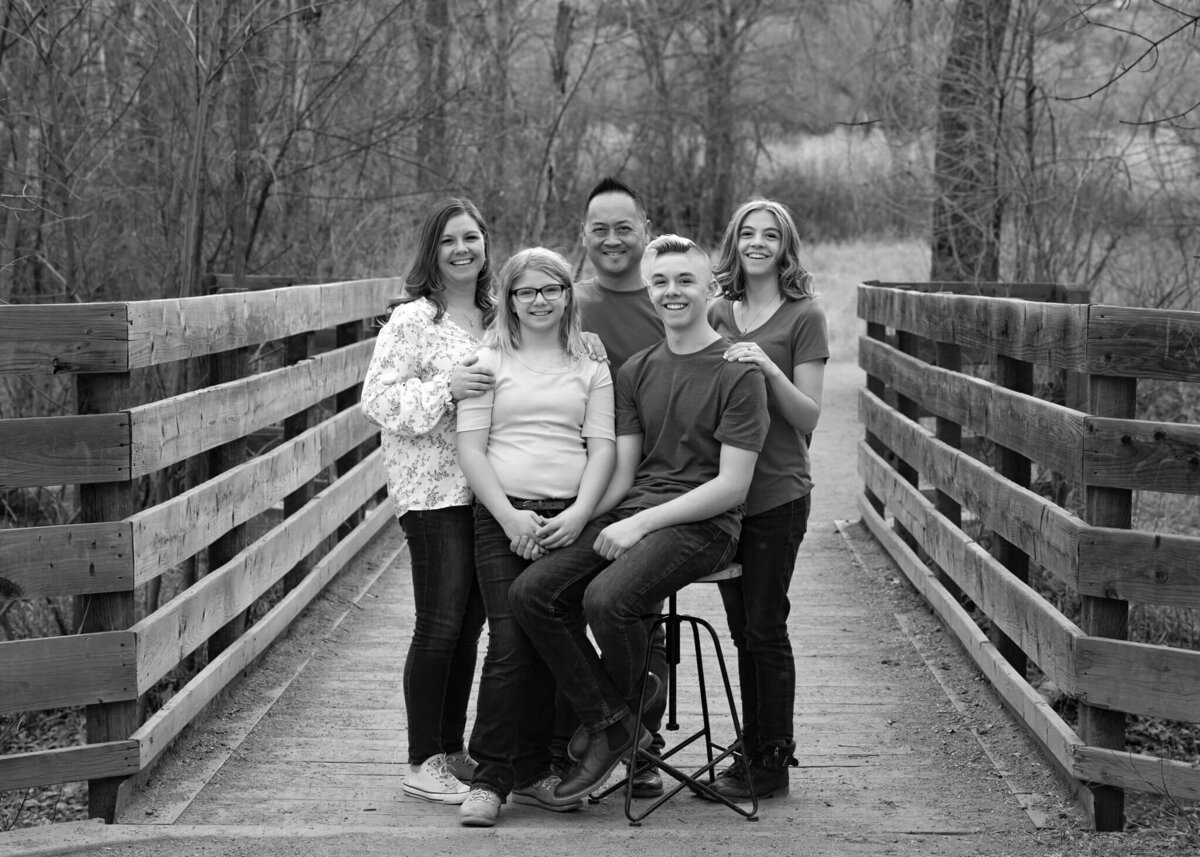 family of five sitting together on a bridge