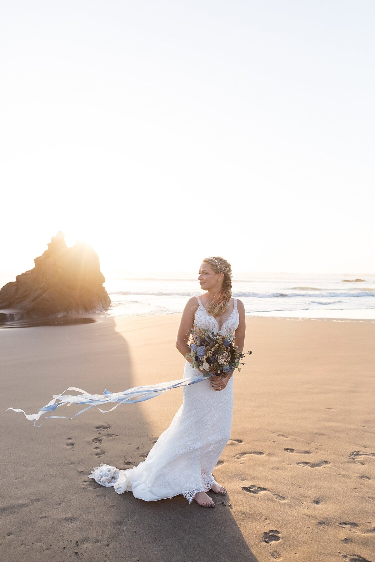 Bride standing on Oregon coast sand in the wind