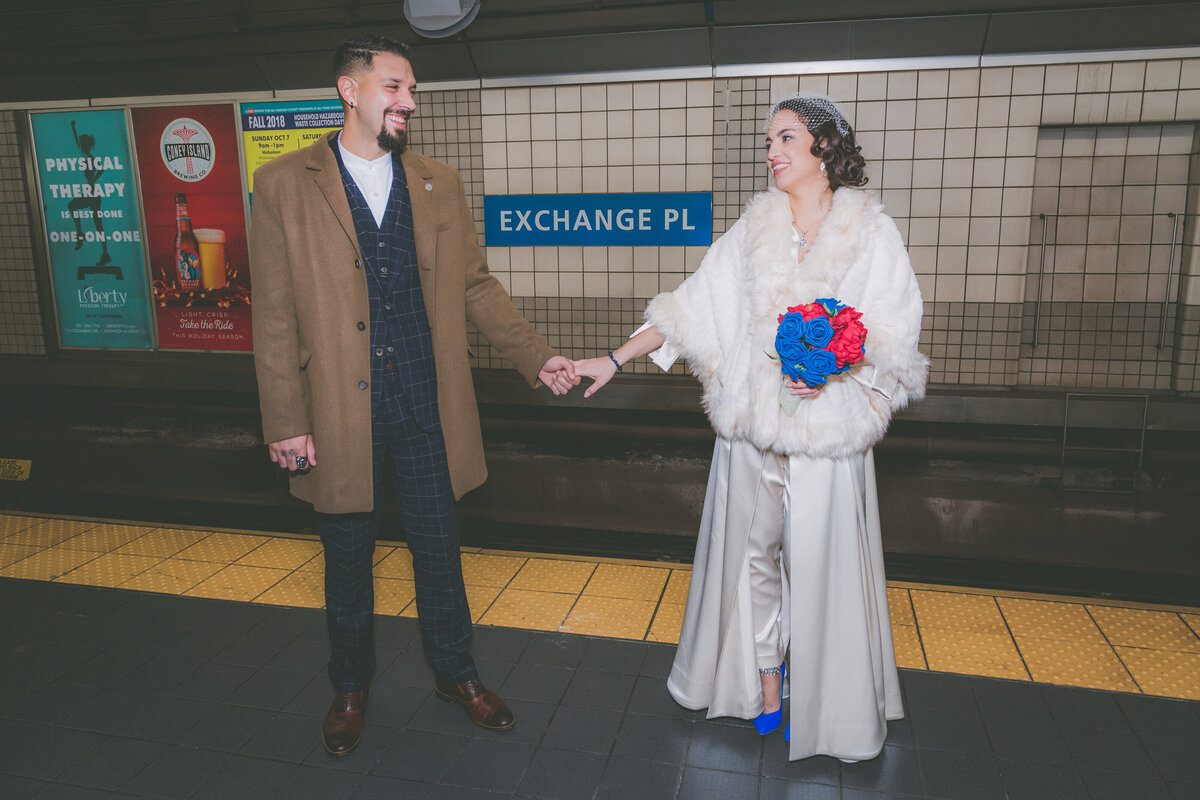 Couple holds hands while waiting for train.