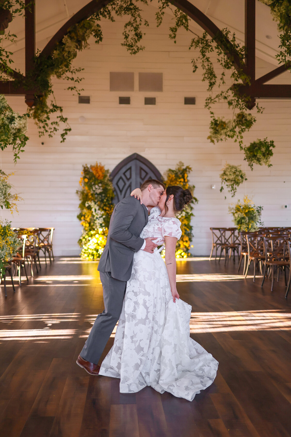 bride and groom kissing in aisle with yellow florals at Hewitt Oaks in Austin Texas by Austin Texas Wedding photographer Amanda Richardson Photography