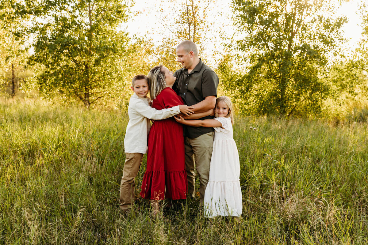 daughter and son hugging their parents in a field for family photos