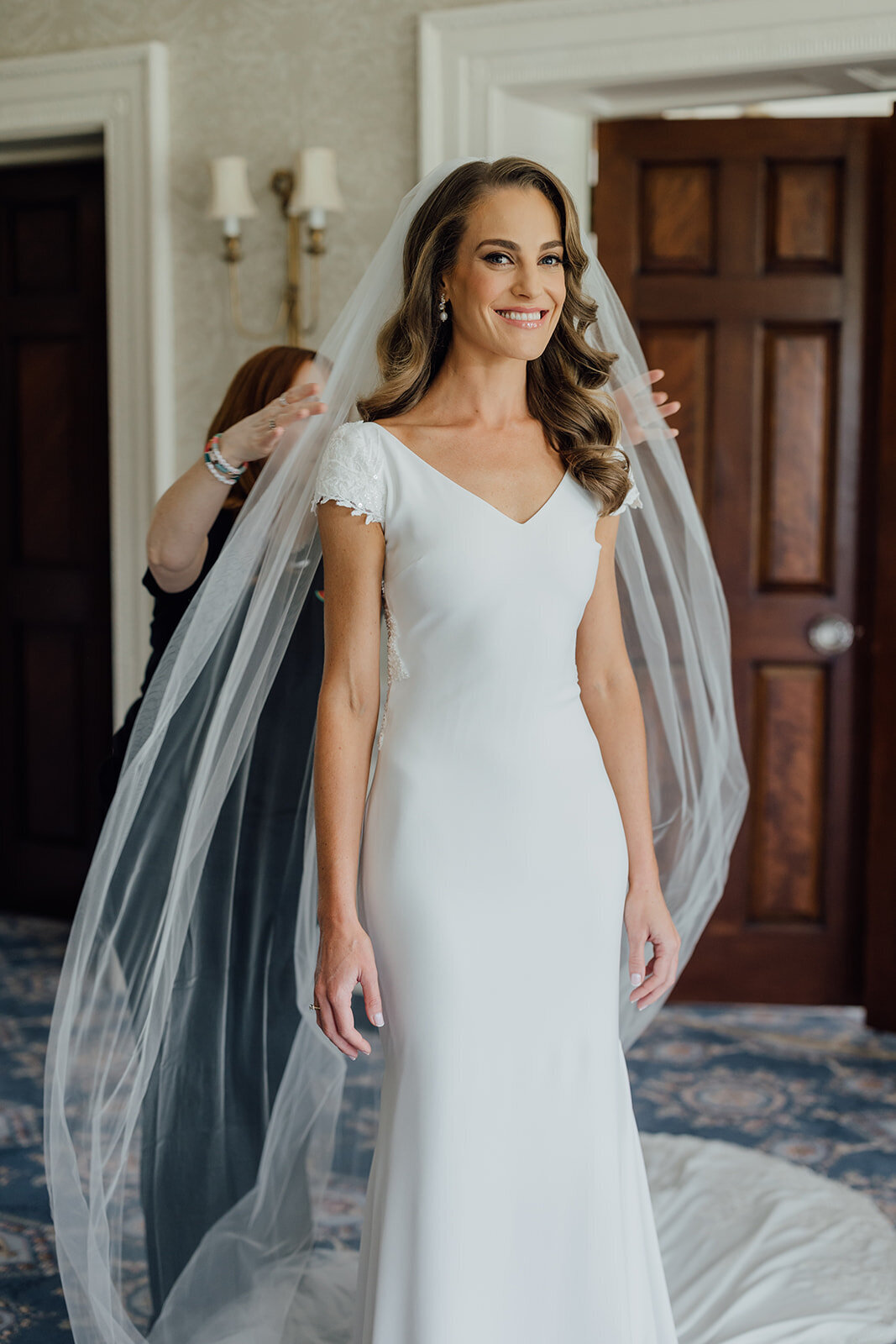 bride-putting-on-long-veil-with-mum