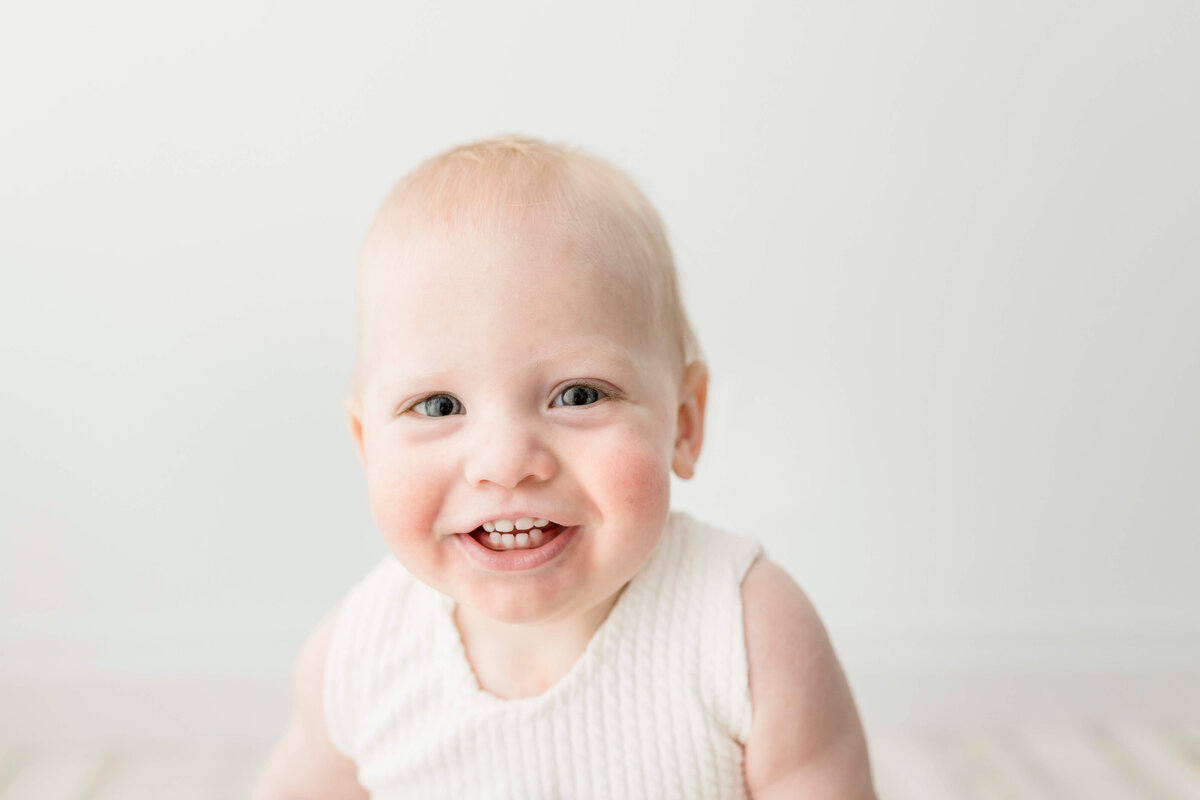 Smiling one year old baby during a smash the cake photo session, captured by Collingwood family photographer Jennifer Wilton