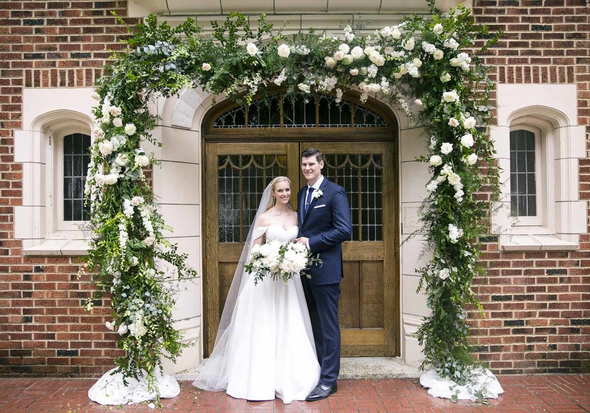 Villa Academy wedding couple at entrance doors with large floral arch above entrance doors
