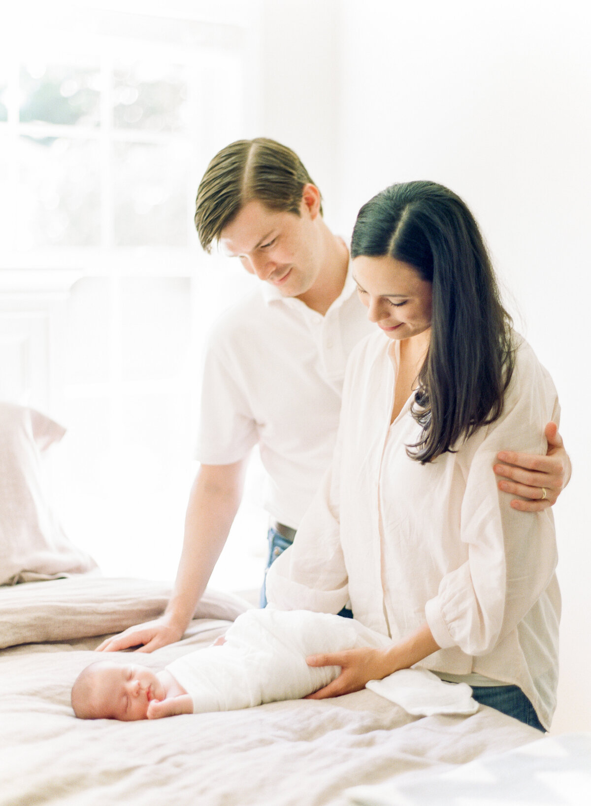 New parents gaze down at their sleeping baby. Image by Raleigh newborn photographer A.J. Dunlap Photography.