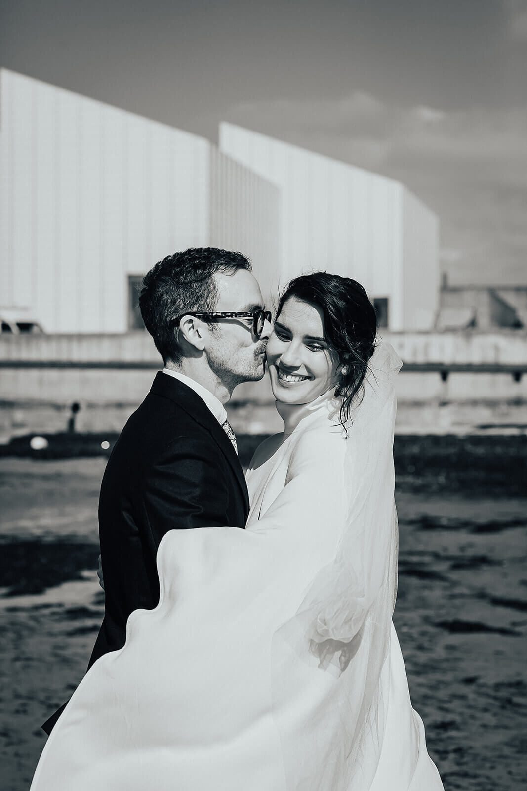 Bride and groom kissing on Margate beach. by Elopement photographer Peach Portman