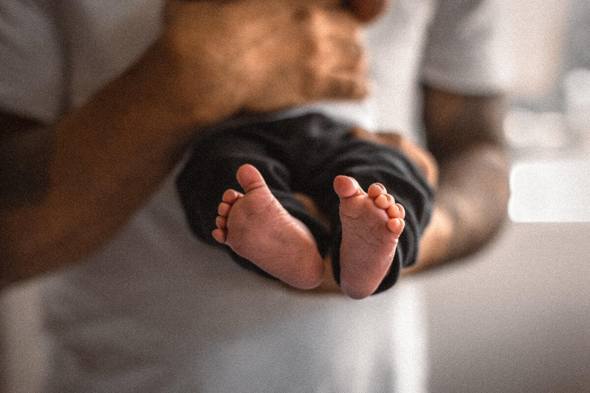 father holding newborn baby feet