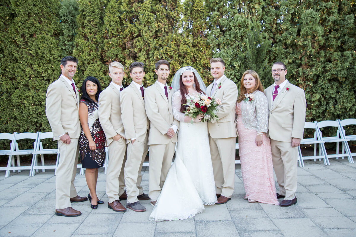 bride and groom with family in cream, white, and pink at their summer garden wedding