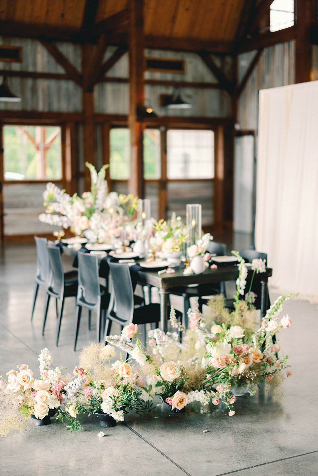 Table decorated with floral centerpieces and large floral arrangements on the floor