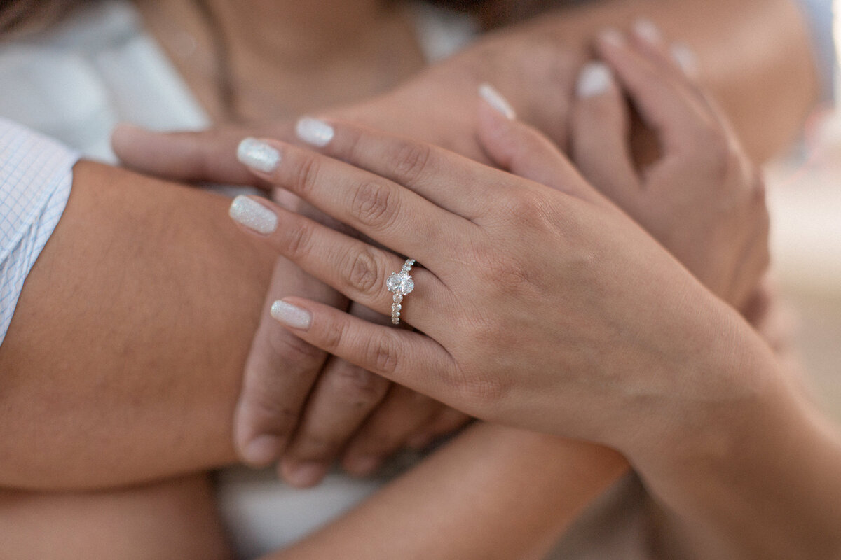 A close up view of an engaged couples hands, displaying their engagement ring