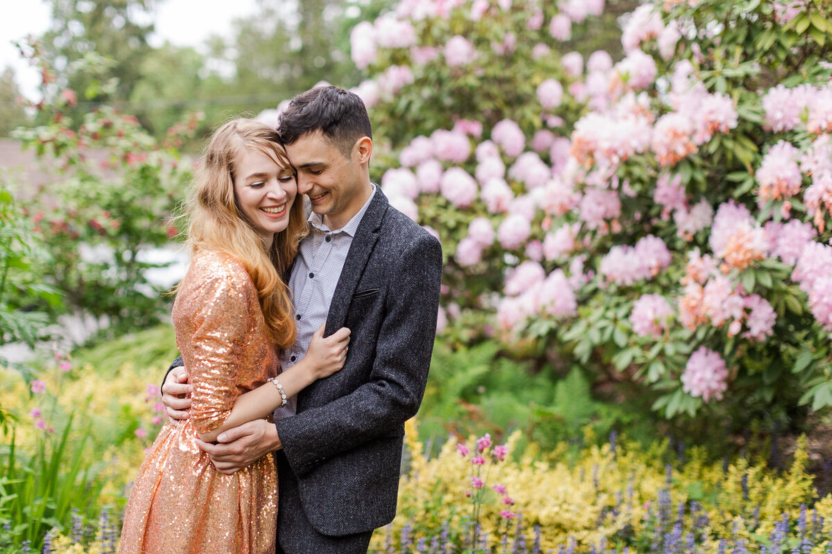 PNW engagement session at Seattle arboretum happy couple smiling and laughing with colorful flowers joyful candid photo by Joanna Monger Photography