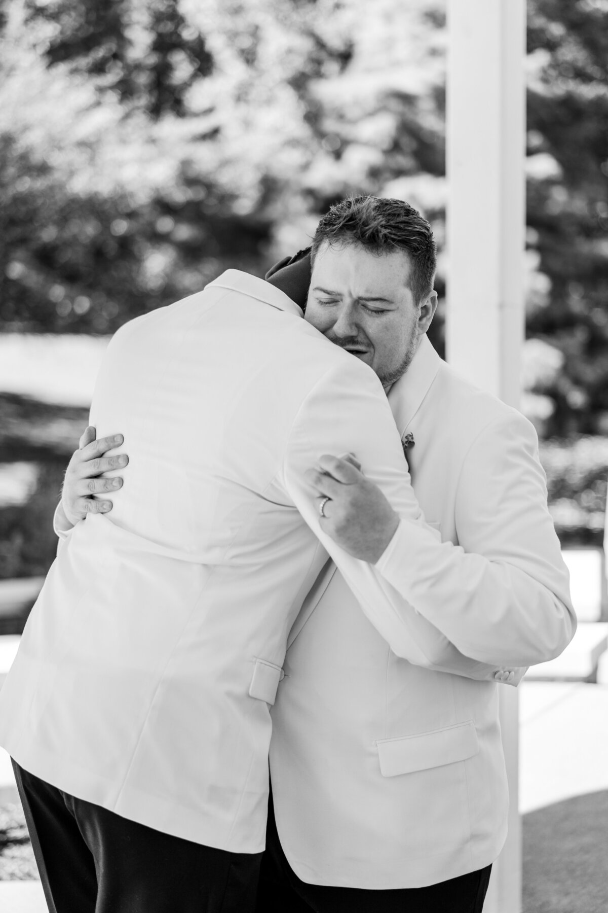 Groom holds his new ring as he gives his groom an emotional hug after he proposed during their first look at Goodale Park in Columbus, Ohio.