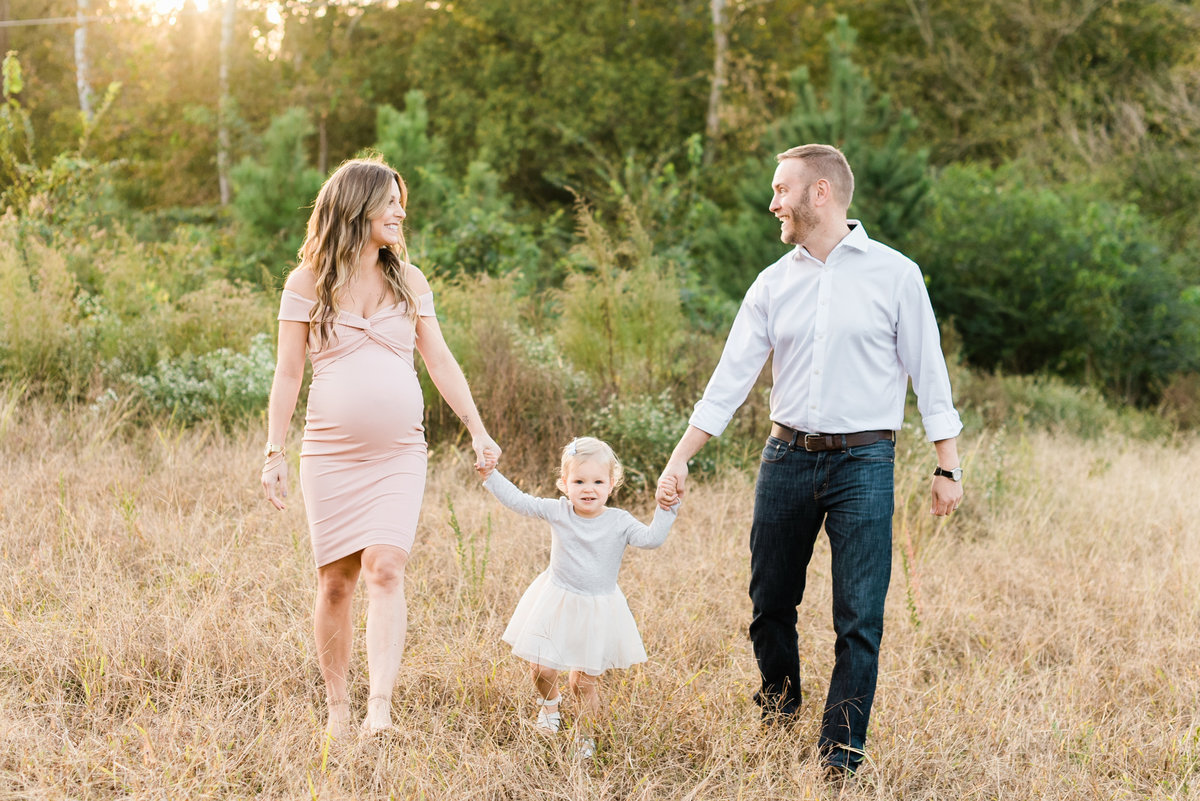 Family walks and holds hands during a Raleigh maternity session. Photographed by Raleigh Maternity Photographer A.J. Dunlap Photography.