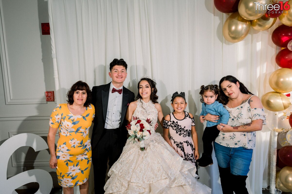 Young lady celebrating her quinceanera poses with her family
