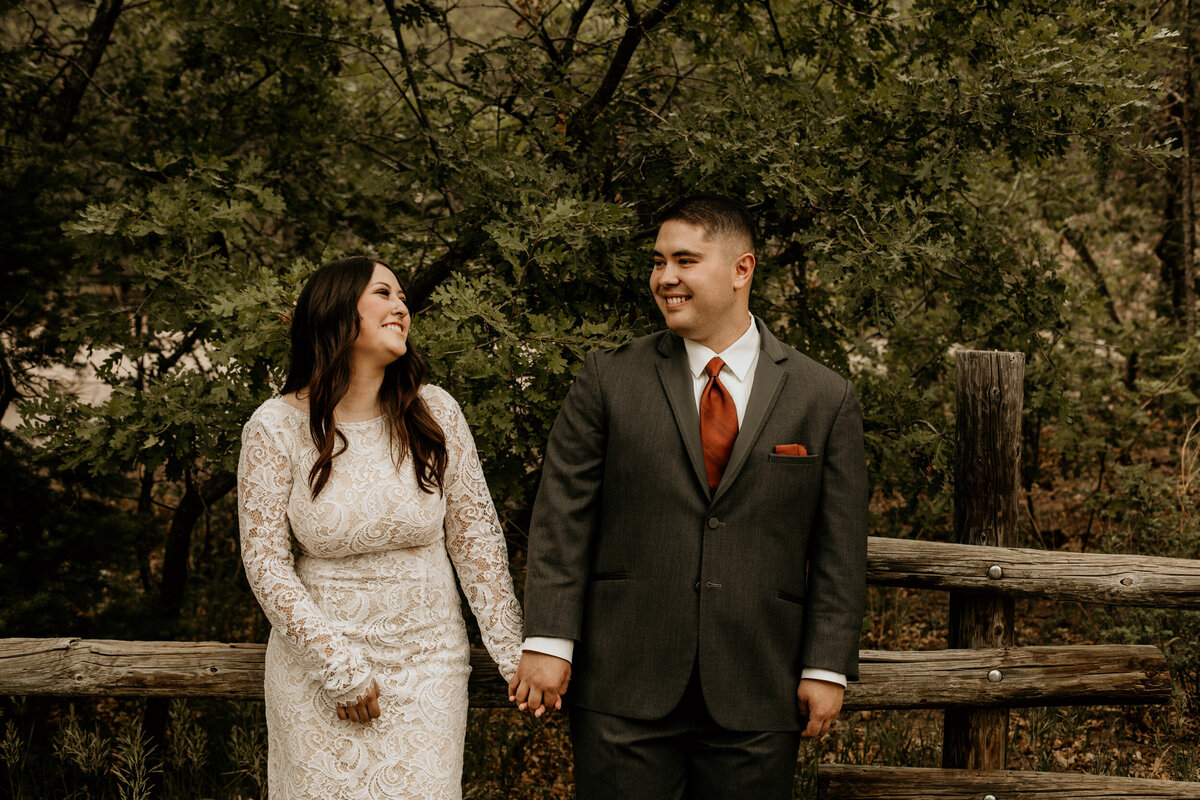 newlyweds leaning against a fence together in new Mexico