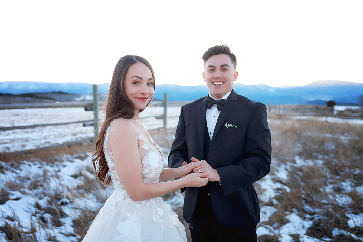 Bride and groom holding hands, in a beautiful snowy mountain setting,