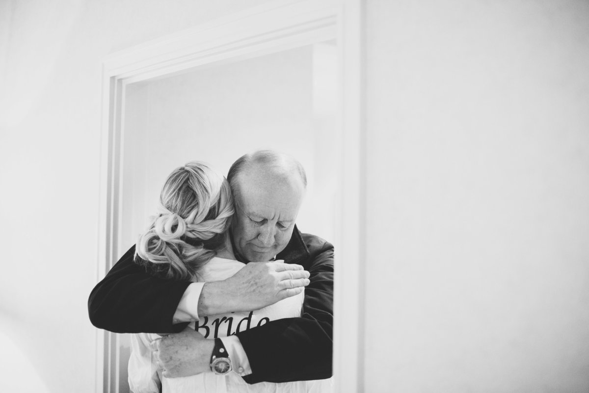 A bride is being hugged by her father in the bridal suite at the hotel in London
