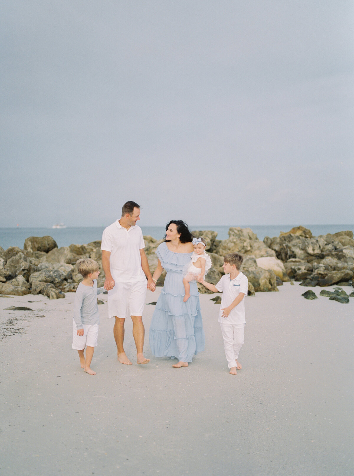 family at the beach smiling and walking by Orlando family photographer