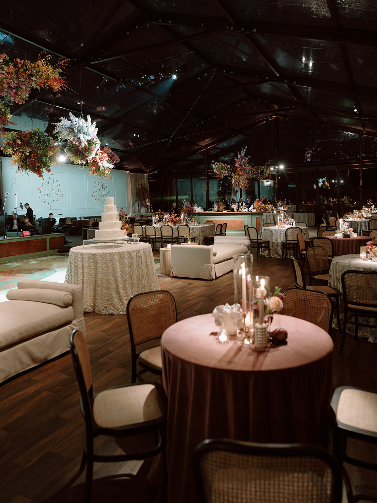 Clustered and styled floral arrangements, fruits, and art pieces for fall wedding reception. Low centerpieces mixed with ikebana arrangements and bud vases decorate the reception tables at this fall wedding. Floral centerpieces featuring orchids, ranunculus, sweet peas, and bittersweet. Styled wedding tables with fruits, curated candles, and floral arrangements. Tasteful fall color palette of copper, ruby, gold, burgundy, rust, and lavender. Design by Rosemary & Finch Floral Design in Nashville, TN.