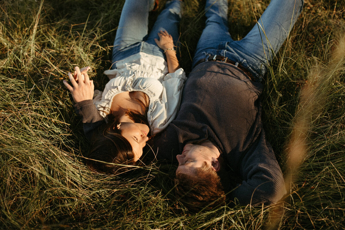 Couple laying in green grass side by side