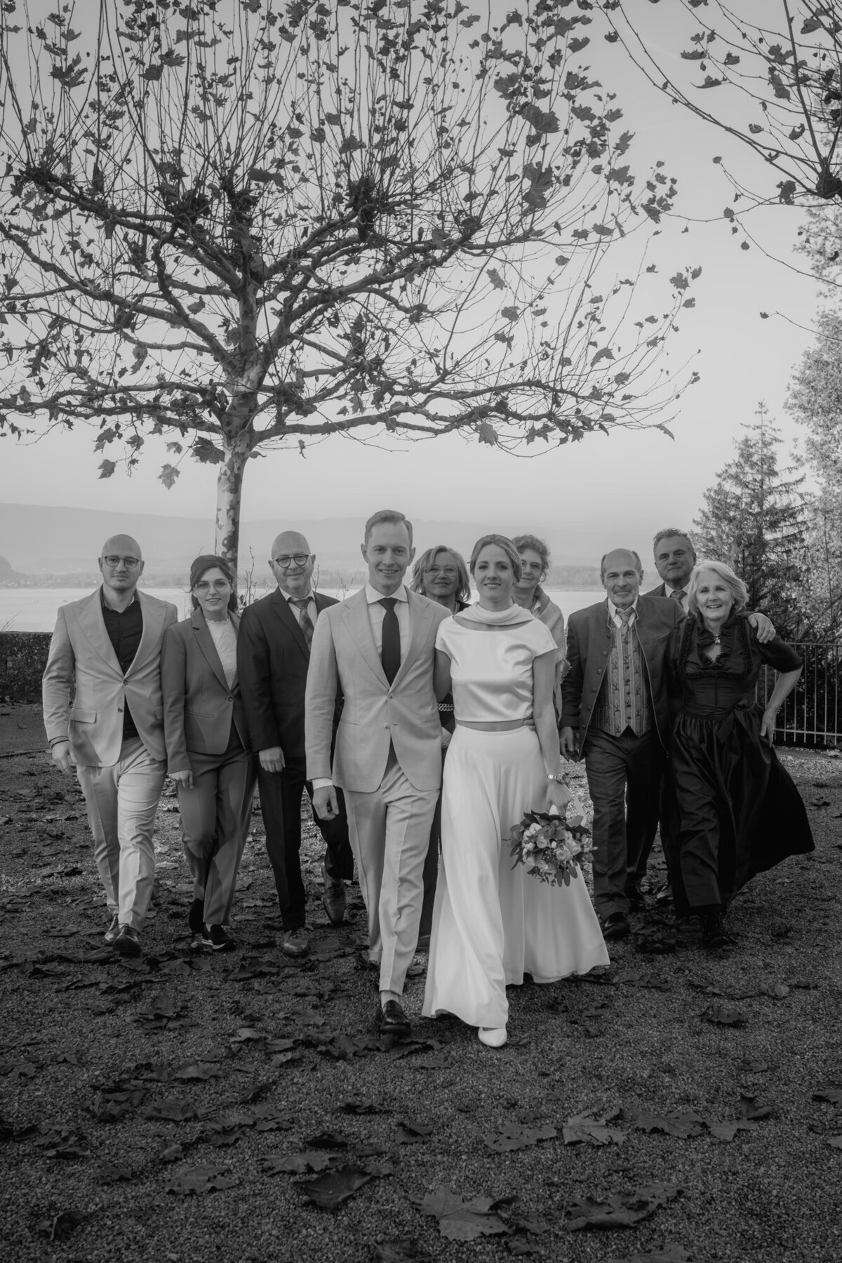 Wedding group photography of the wedding couple with their guests walking towards the wedding photographer.
